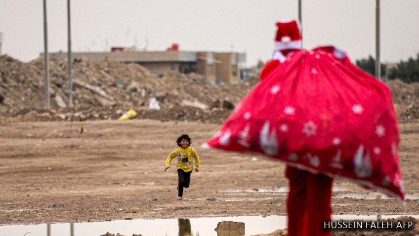 Un niño corre hacia Papá Noel, en un barrio pobre cerca del centro de la ciudad de Basora, en el sur de Irak, el 24 de diciembre.