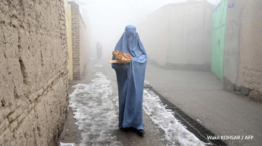 Una mujer con burka camina por una calle hacia su casa después de recibir pan gratis en Kabul