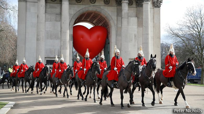 Los jinetes de la Caballería pasan junto al Arco de Wellington y un gran corazón inflable, el Día de San Valentín en Londres, Gran Bretaña