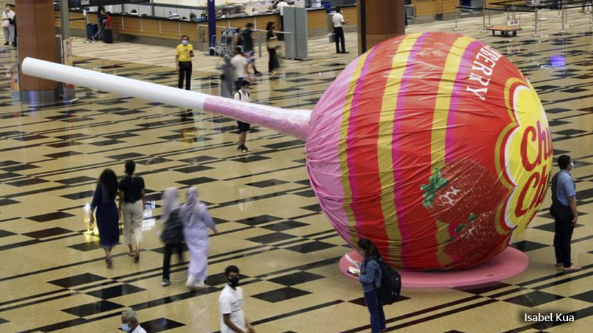 La gente pasa por una paleta gigante en exhibición en el aeropuerto Changi de Singapur