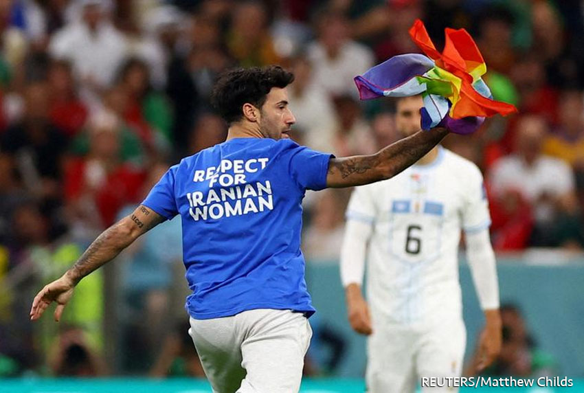 Un aficionado invade la cancha con una camiseta de respeto por la mujer iraní y sosteniendo una bandera con los colores del arcoíris durante el partido entre Portugal y Uruguay