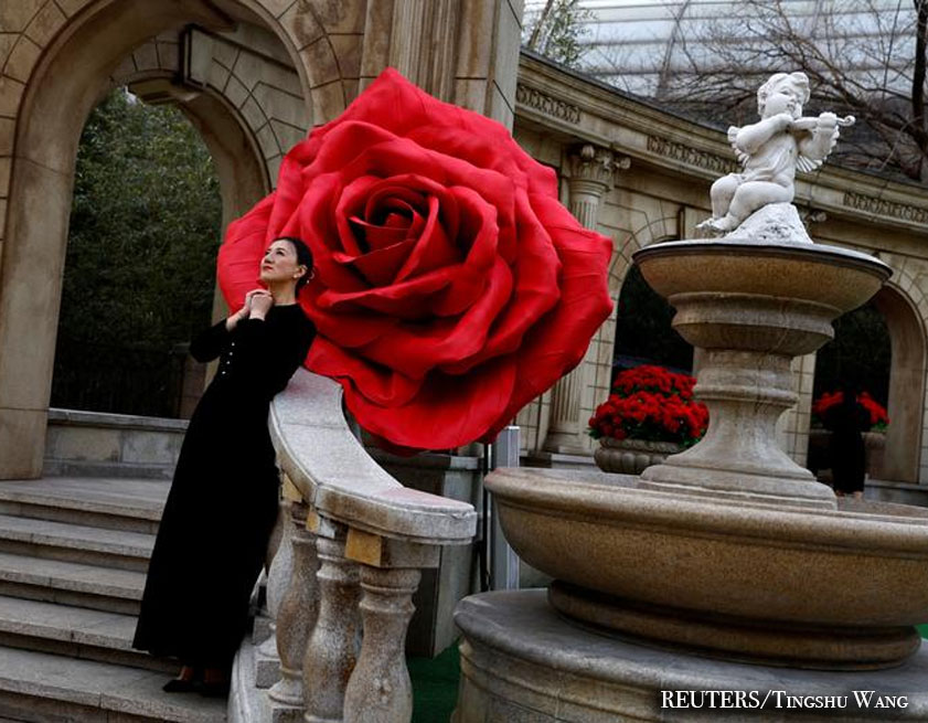 Una mujer posa para fotografías frente a instalaciones de rosas gigantes en el Día de San Valentín en Beijing, China.