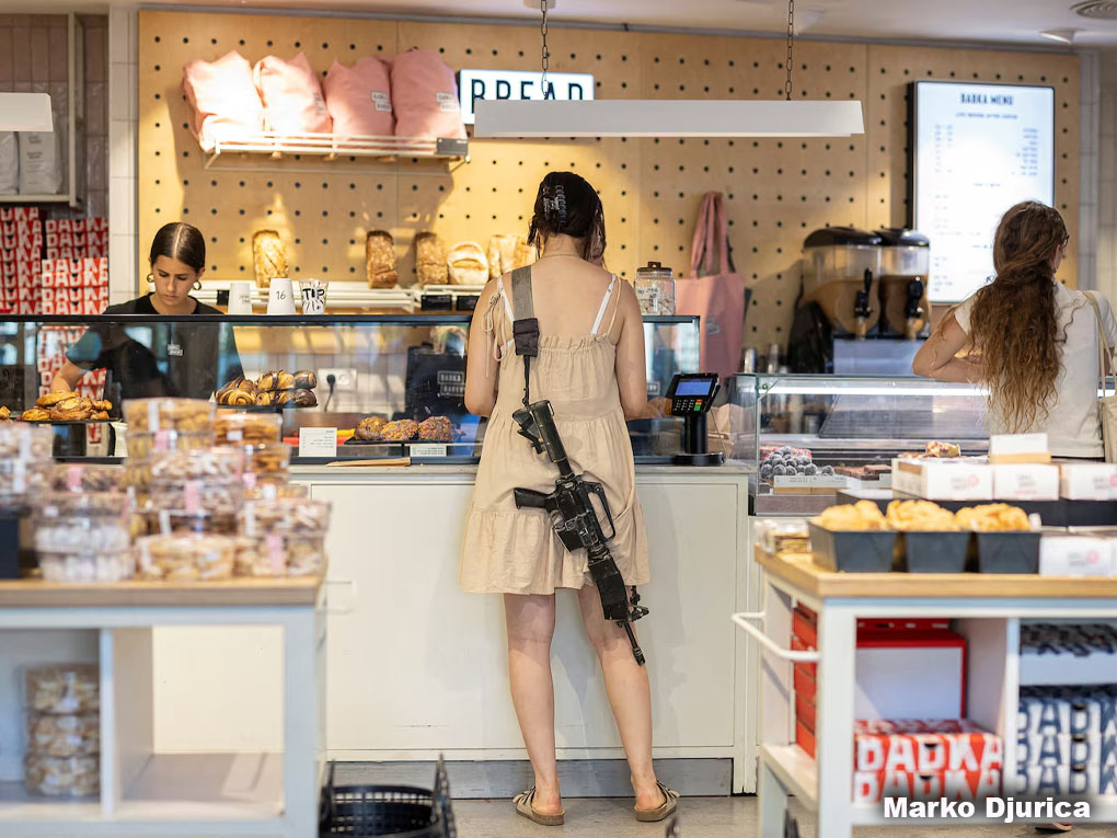 Una mujer con un rifle compra en una panadería, en medio del actual conflicto entre Israel y Hamás, en Tel Aviv, Israel. REUTERS/Marko Djurica