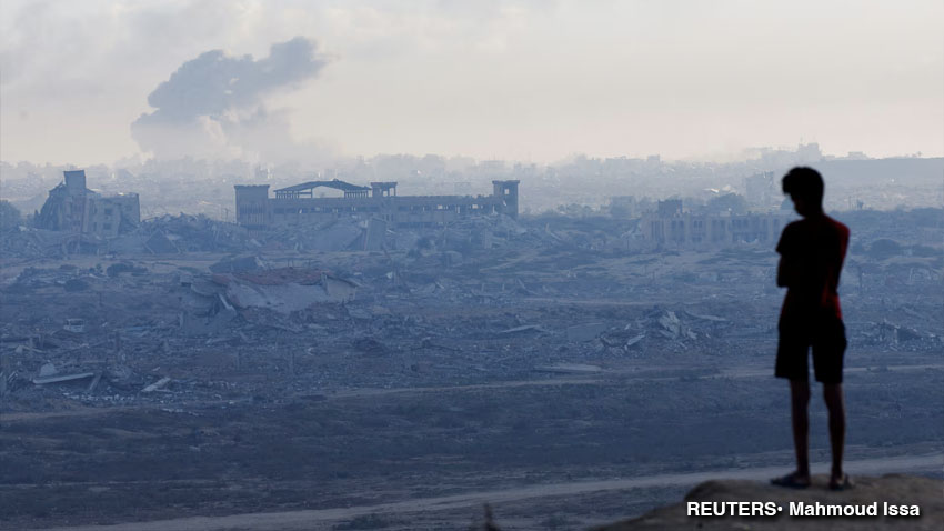 Un niño palestino desplazado observa cómo se eleva el humo durante una operación militar israelí en la ciudad de Gaza, vista desde el centro de la Franja.