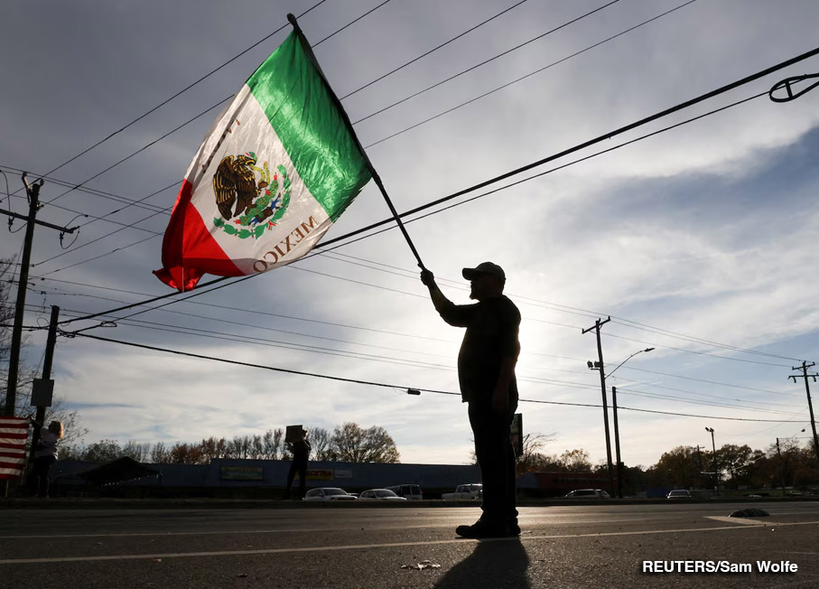 Un manifestante ondea una bandera mientras miembros del Servicio de Aduanas y Protección Fronteriza de Estados Unidos (CBP) realizan redadas migratorias en las calles de Charlotte, Carolina del Norte